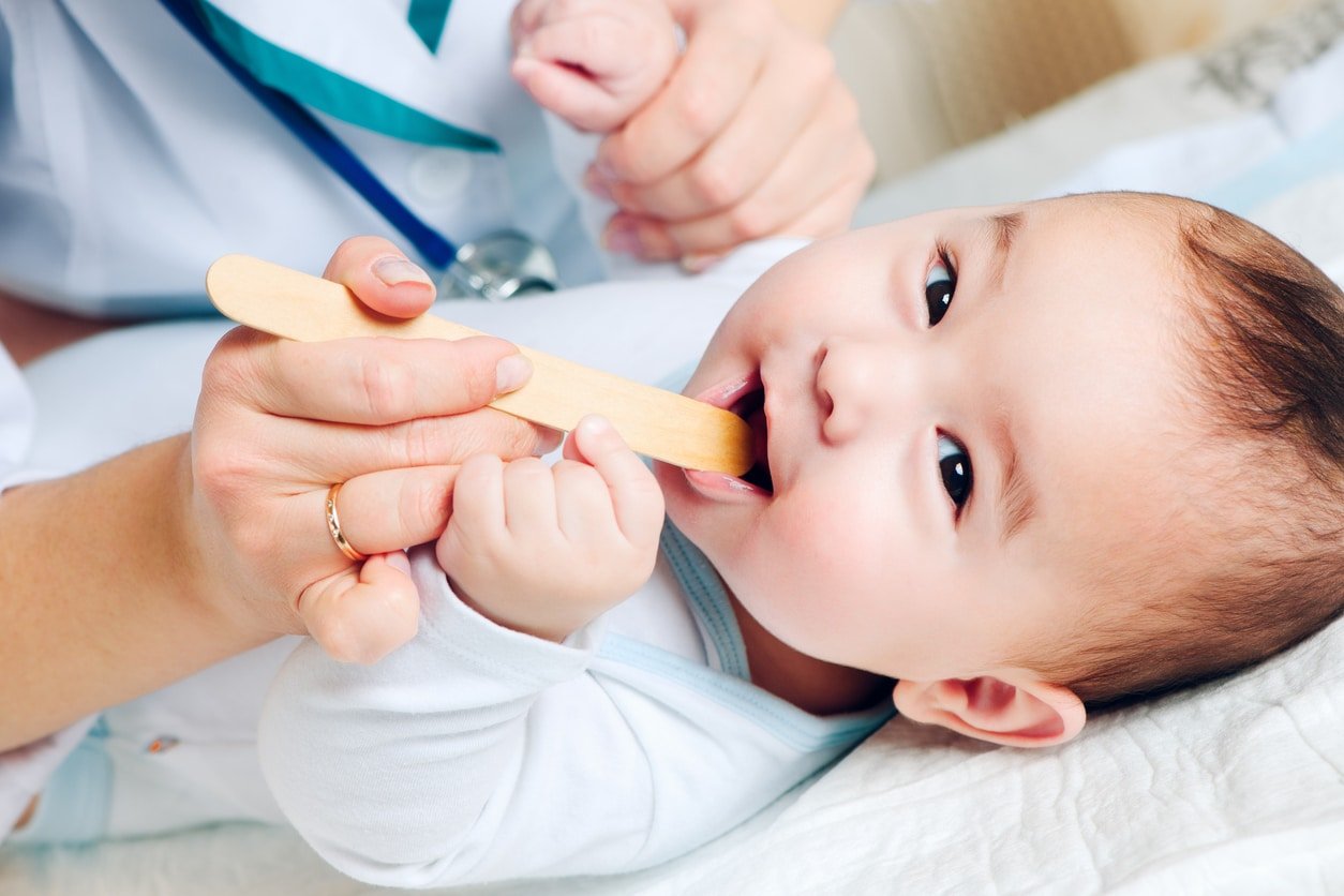Pediatrician checking throat of cute baby