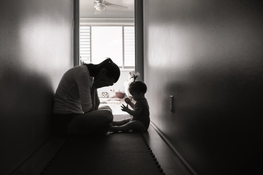 Sad and tired mother with her baby girl at home.