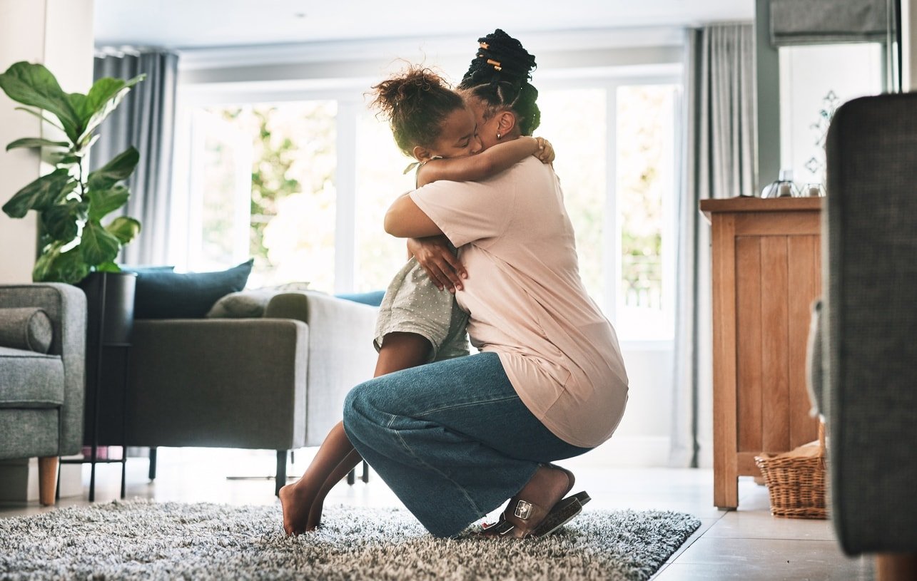 Shot of a mother and child hugging at home in the living room.