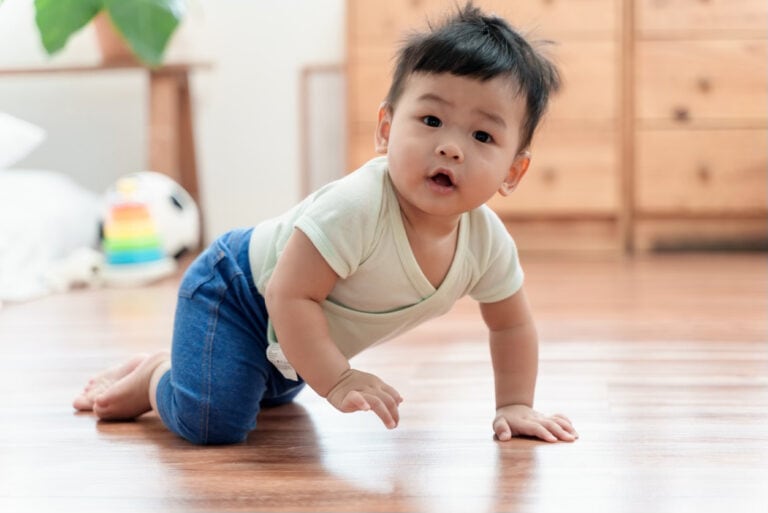 Adorable Asian baby boy crawling on floor, Smiling and looking at camera.