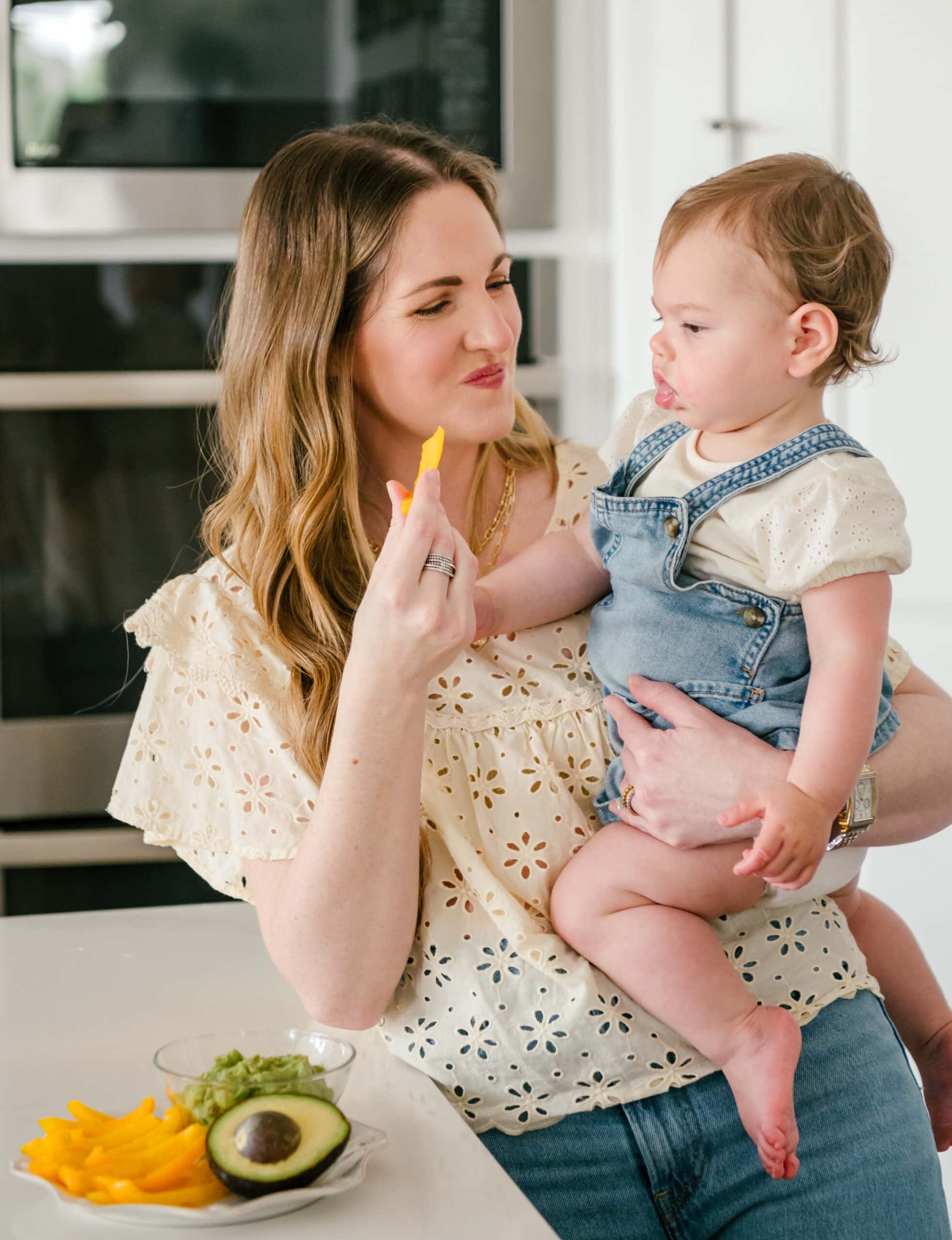 Young mom eating a healthy snack while holding her baby girl