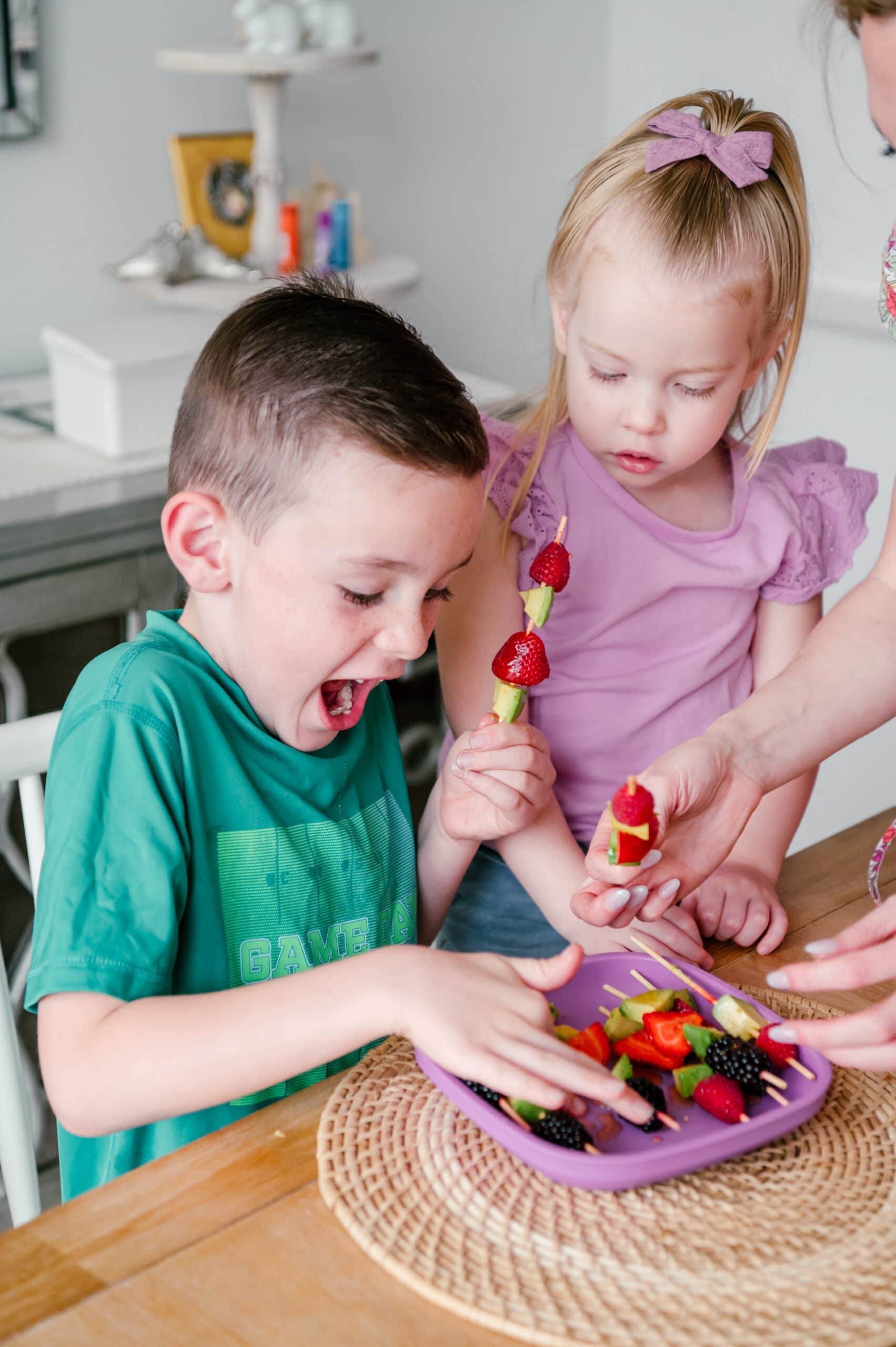 Kids eating an avocado and berry snack on skewers