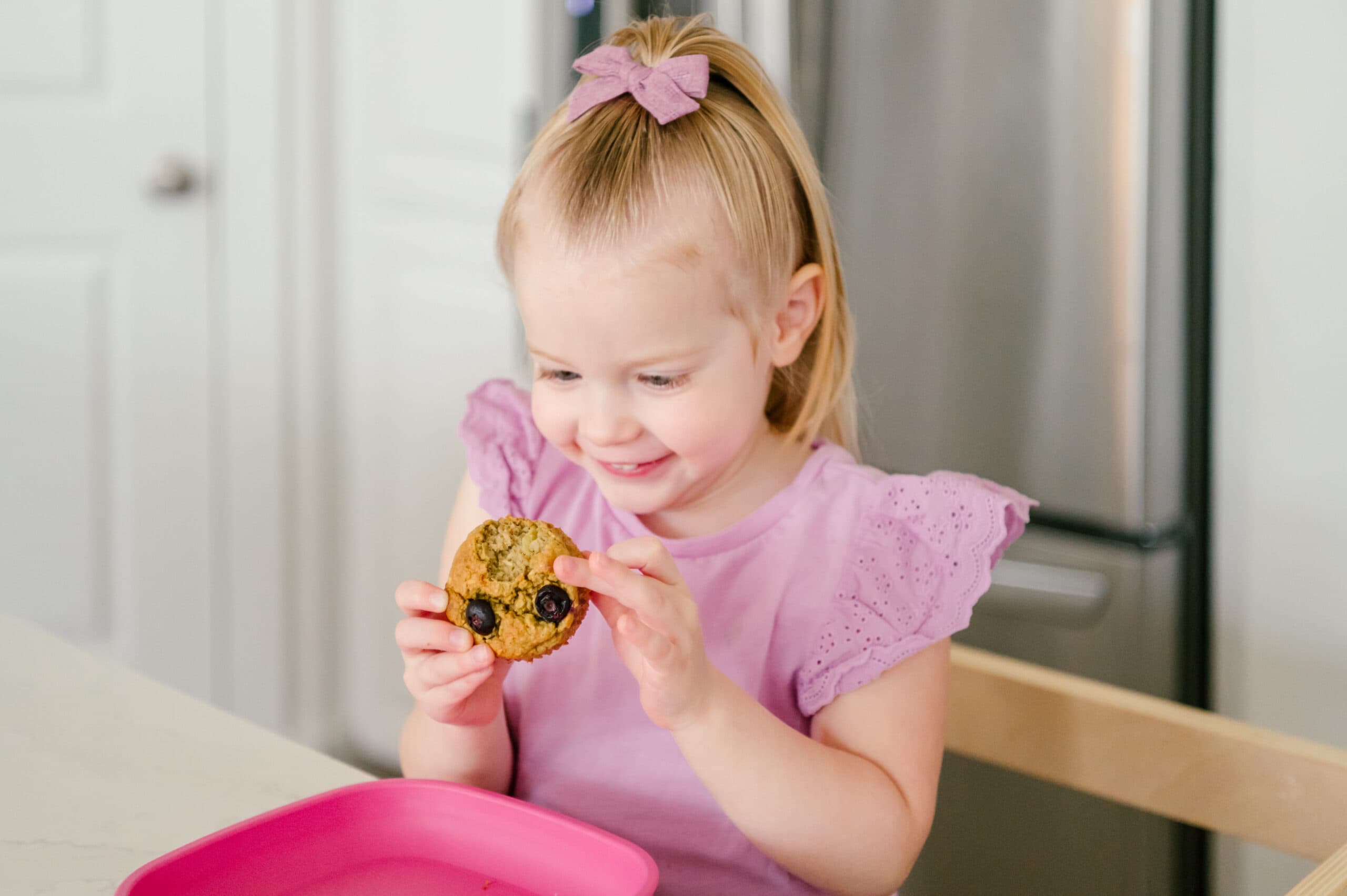 Little girl looking at a muffin she is holding
