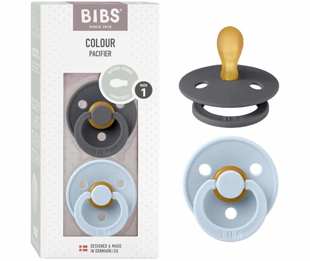 Image of a product package for BIBS Colour Pacifier, featuring two pacifiers in gray and light blue. The package indicates they are Size 1 and made of natural rubber. Perfect for postpartum essentials, the gray pacifier is displayed outside the packaging. Made in Denmark/EU is noted.