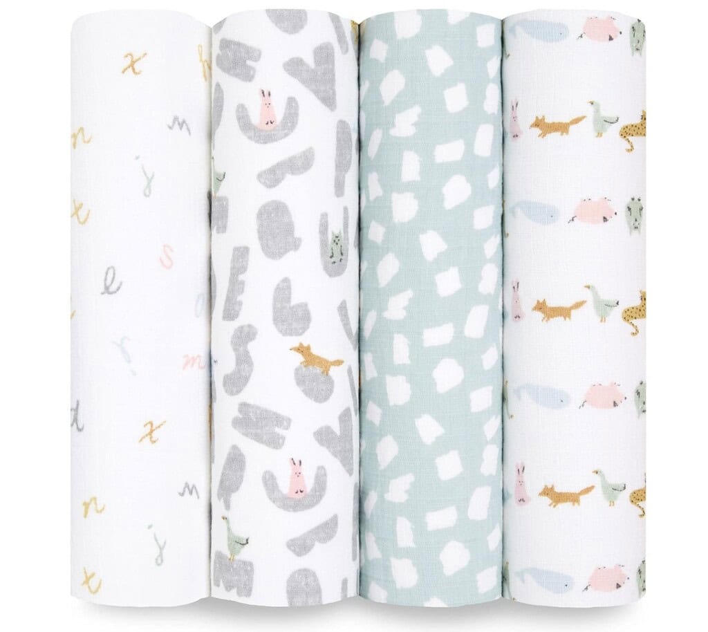 Four rolled-up baby swaddle blankets are displayed, perfect for postpartum recovery. They feature various designs: white with pastel letters, grey and white with animals, pale green with white geometric shapes, and white with pastel animal illustrations. These are truly postpartum essentials.
