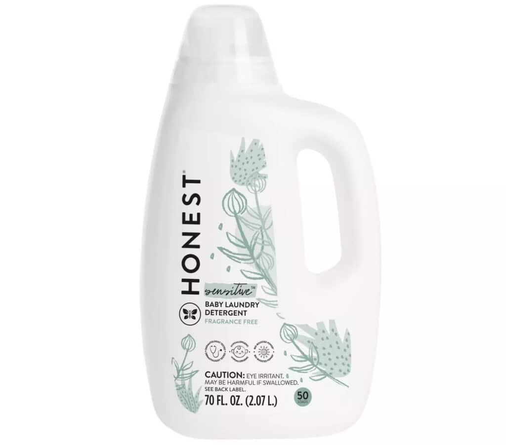 A 70 fl. oz. bottle of Honest brand baby laundry detergent, labeled sensitive and fragrance-free—perfect for postpartum essentials. The white bottle with green plant illustrations can handle 50 loads and includes caution for eye irritation and harmful if swallowed.