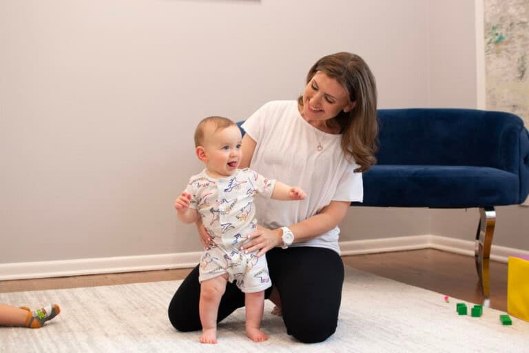 Dr. Allison Mell working with a baby on the floor with their development skills as a pediatric physical therapist.