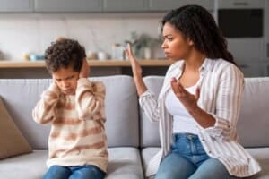 Mother arguing with son about misbehavior in living room.