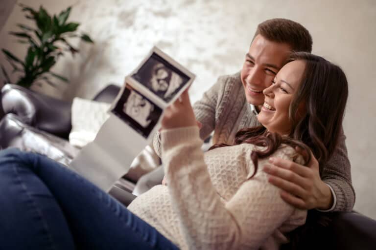 Cute baby chick ultrasound, pregnant woman and partner happily examining baby scans.